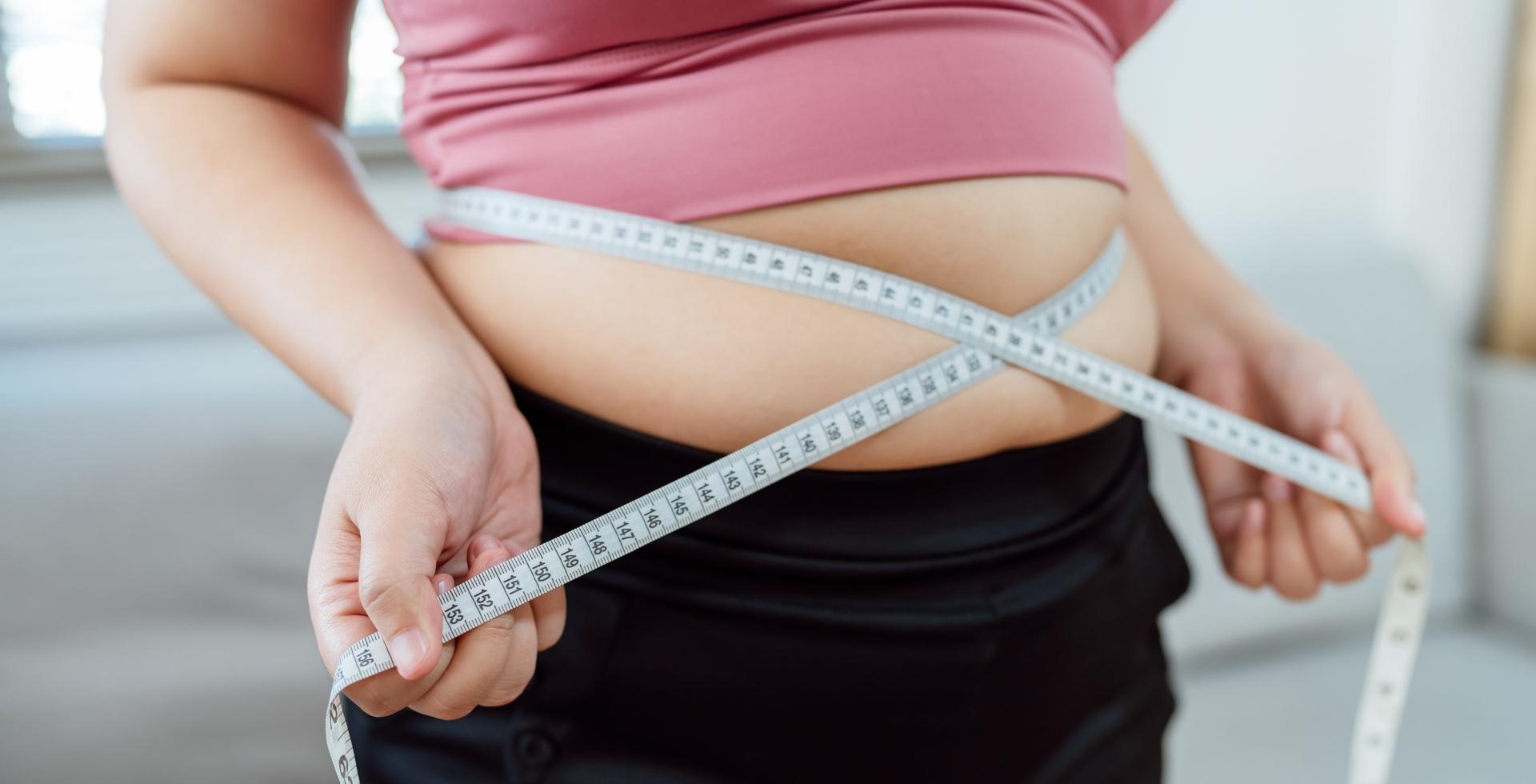mujer midiendose la cintura por la grasa abdominal